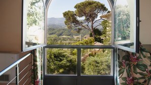 A room with a large arched window offering a view of a tree and landscape. - Relais Villa Belpoggio - Residenza d'Epoca (Loro Ciuffenna)