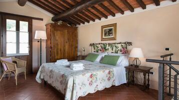 Una camera da letto con un letto, una testiera in legno, una sedia, un comodino e una lampada.