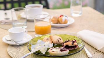 A table set with a plate of pastries, a glass of orange juice, and a cup of coffee.