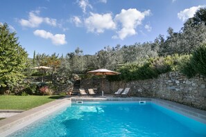 A rectangular swimming pool with a stone wall and a grassy area with lounge chairs and umbrellas. - Relais Villa Belpoggio - Residenza d'Epoca (Loro Ciuffenna)