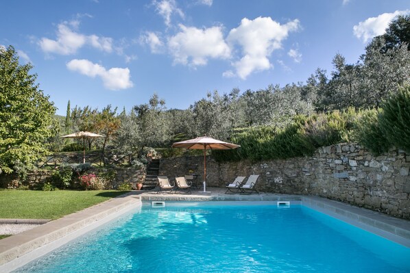 A rectangular swimming pool with a stone wall and a grassy area with lounge chairs and umbrellas. - Relais Villa Belpoggio - Residenza d'Epoca (Loro Ciuffenna)