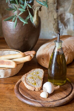 A wooden table with bread, garlic, and a bottle of olive oil. - Relais Villa Belpoggio - Residenza d'Epoca (Loro Ciuffenna)