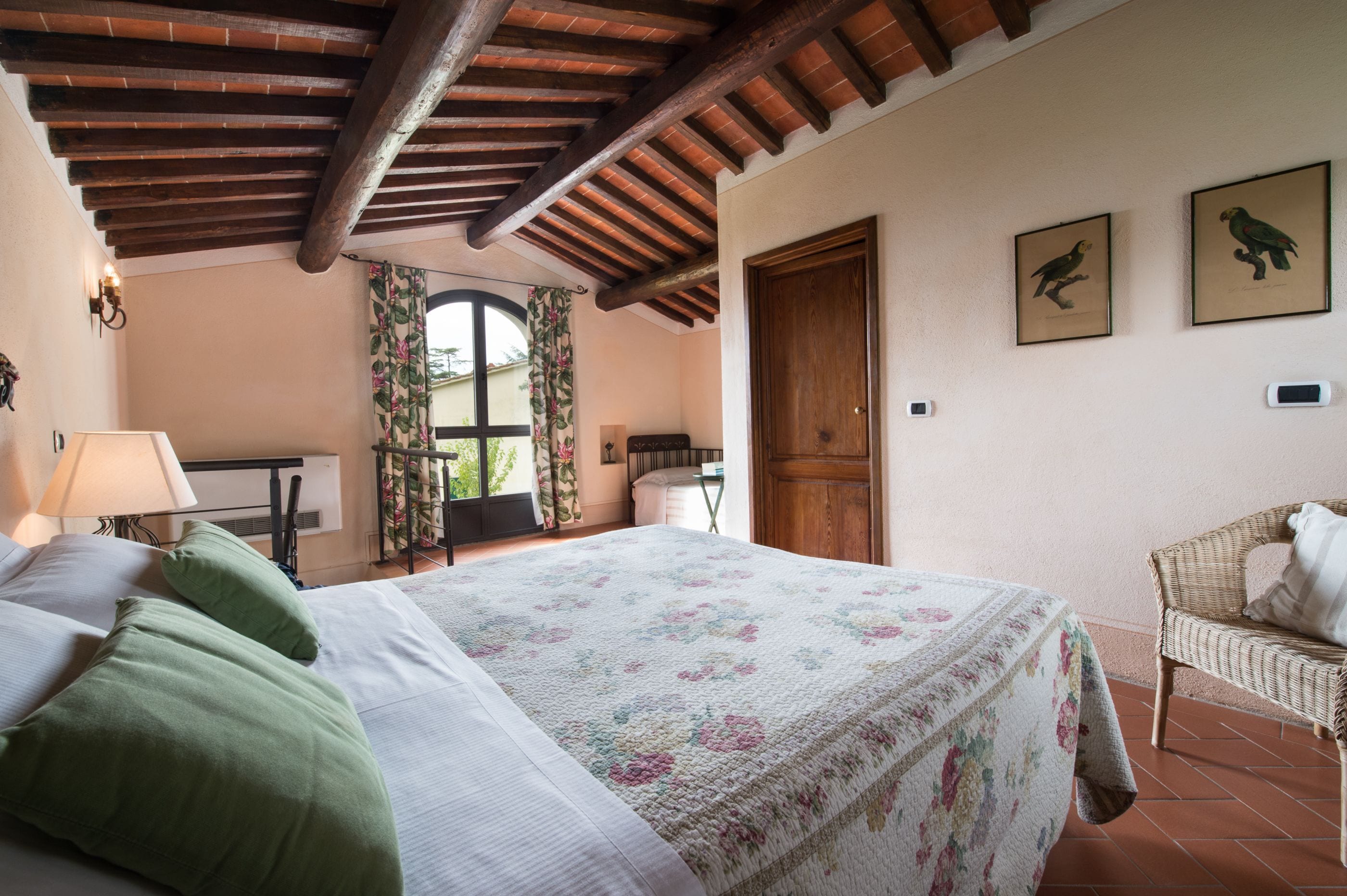 A bedroom with a bed, a chair, a window with curtains, and a door.