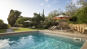 A swimming pool with lounge chairs and umbrellas, surrounded by greenery and a stone wall. - Relais Villa Belpoggio - Residenza d'Epoca (Loro Ciuffenna)