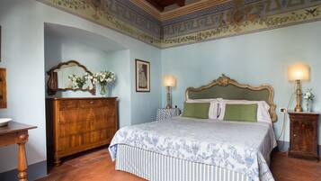 A bedroom with a large bed, wooden dresser, and two bedside tables with lamps.