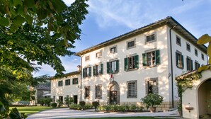 A two-story building with a symmetrical facade, green shutters, and a central arched entrance. - Relais Villa Belpoggio - Residenza d'Epoca (Loro Ciuffenna)