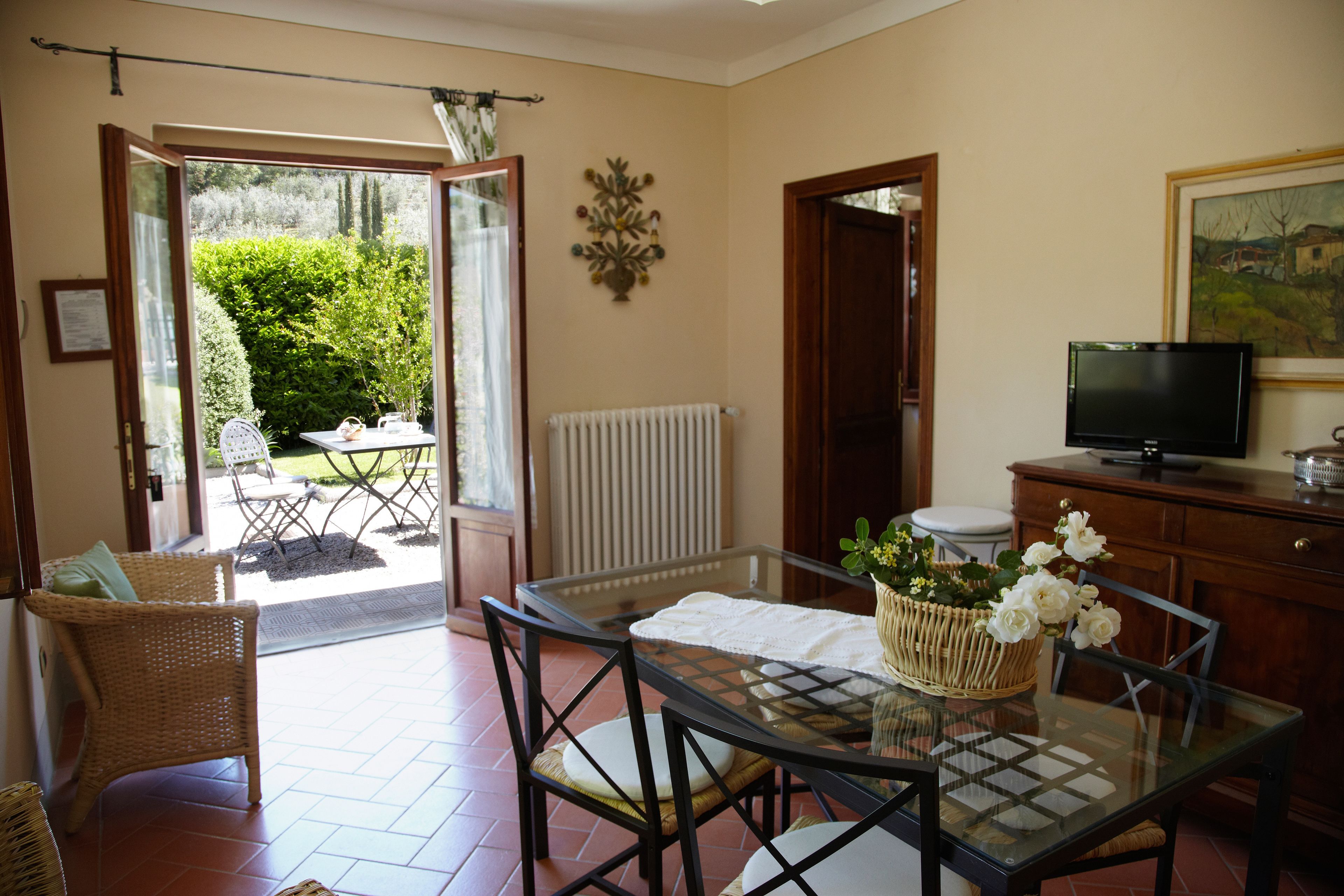 A dining area with a glass table, wicker chairs, and a wicker basket with flowers.