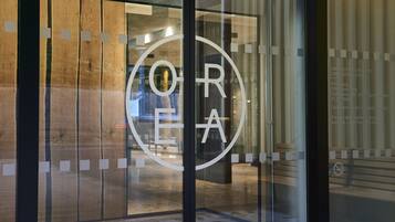 L’entrée d’un hôtel, avec un logo circulaire apposé sur la porte en verre.