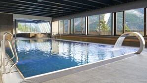 Una piscina interior con agua cristalina, una escalera de metal y vistas a un paisaje montañoso a través de amplios ventanales.