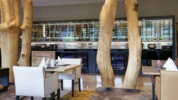 A restaurant interior with wooden pillars, tables, chairs, and a wine display.