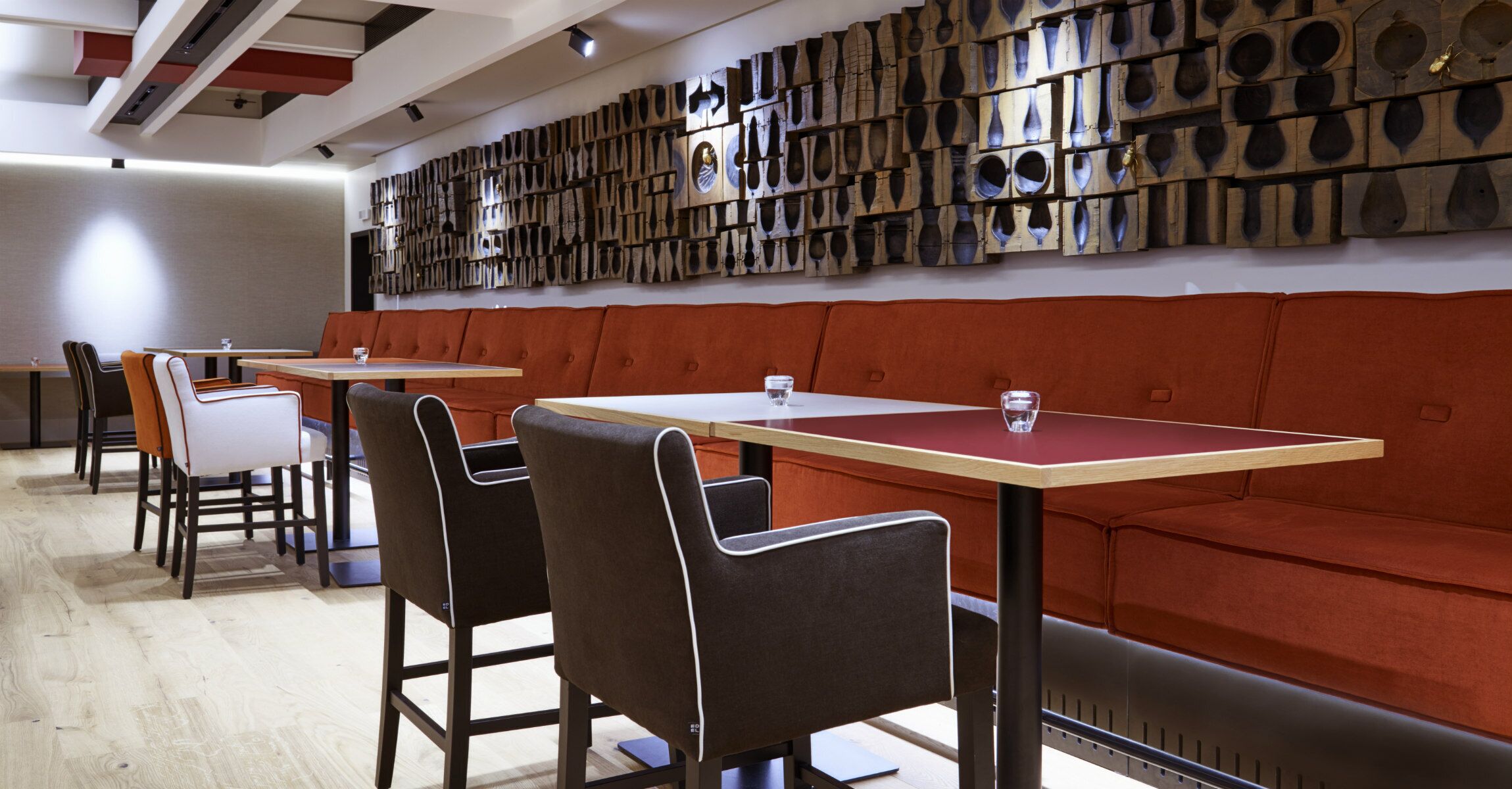 Interior de restaurante con cabinas, mesas y una pared de adornos de madera.