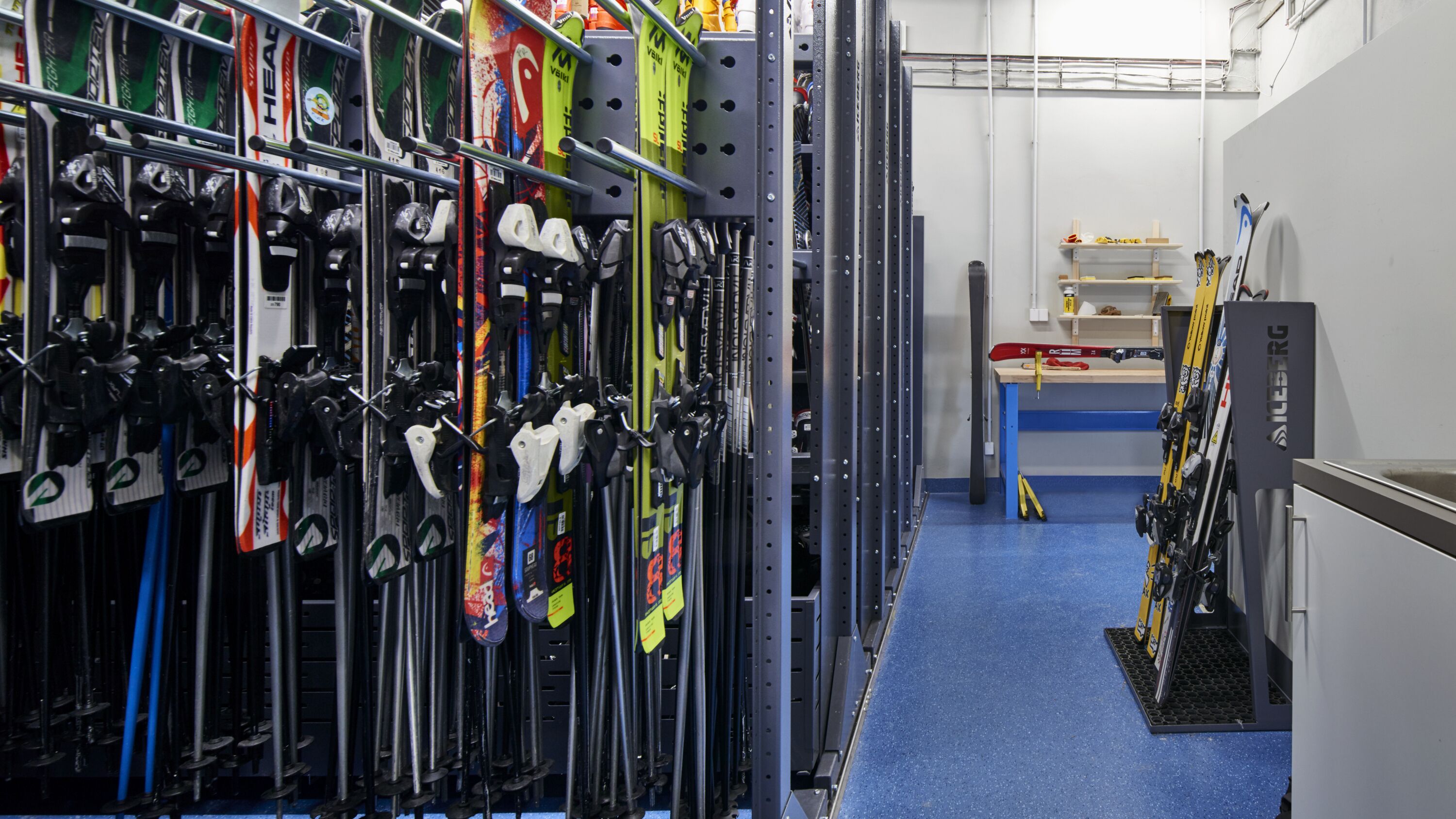 Uma sala para guardar equipamentos de esqui, com esquis e bastões de esqui organizados em suportes.