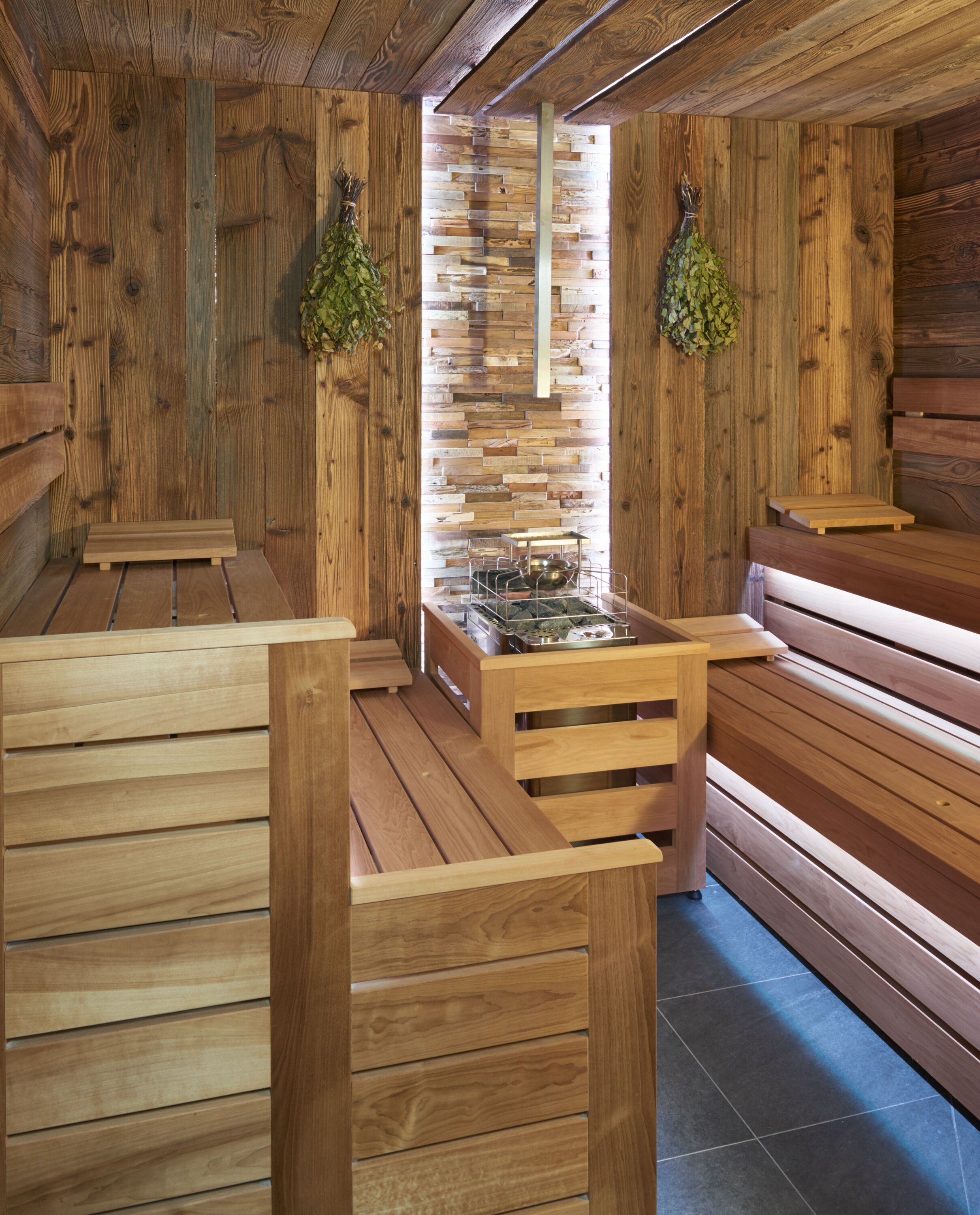 Eine Sauna mit Holzbänken und einer Steinwand.