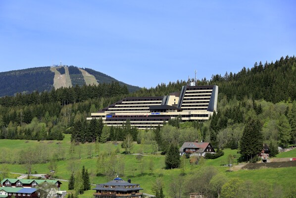 A hotel with a modern design, situated on a hillside with a view of a mountain.