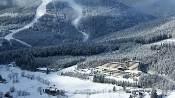 A large, multi-story building surrounded by snow-covered forested hills.