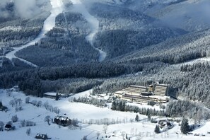 A large, multi-story building surrounded by snow-covered forested hills.