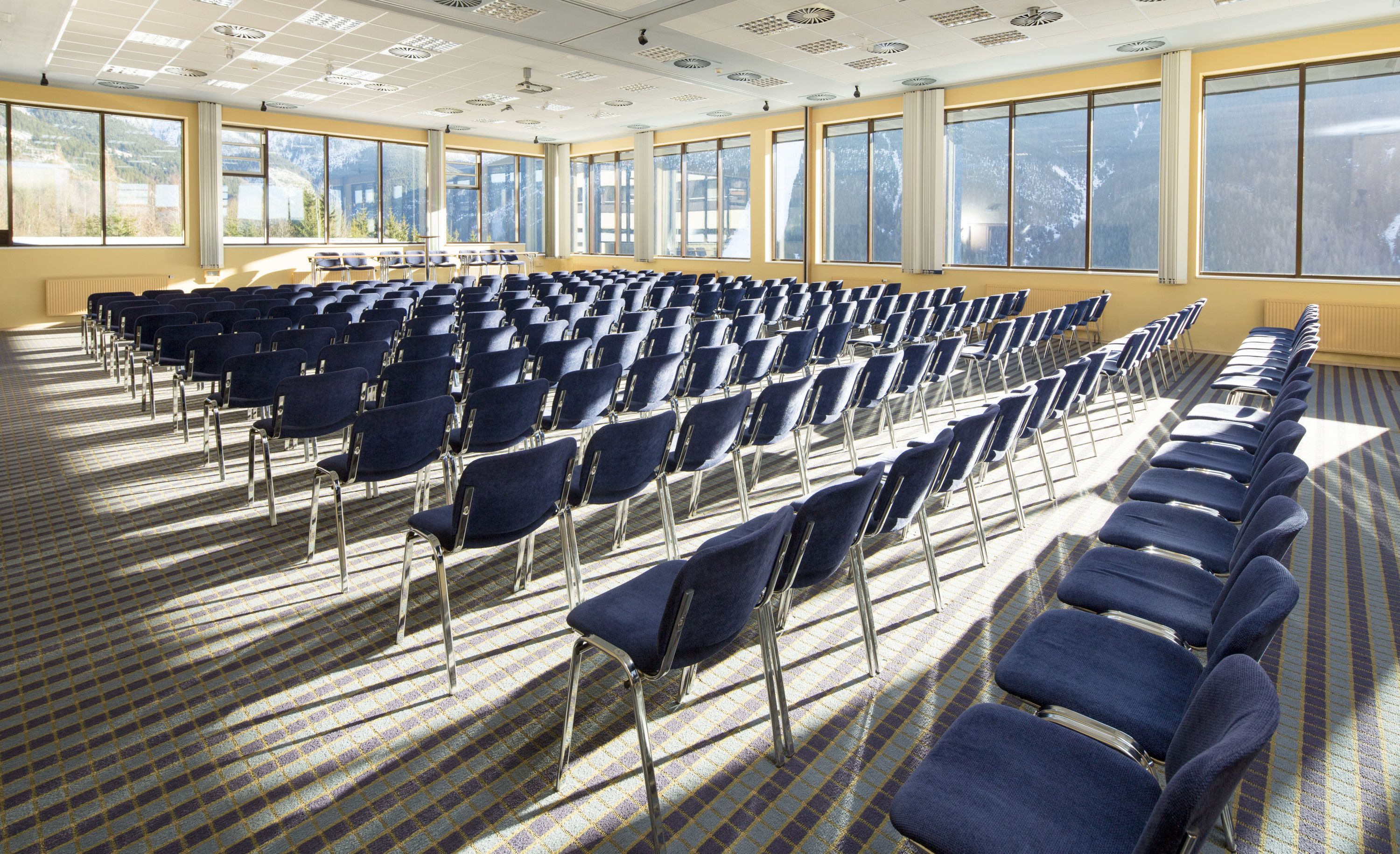 A conference room with rows of chairs and large windows.