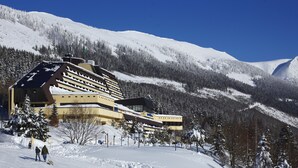 Un hotel grande con varios pisos y una pista de esquí al fondo.