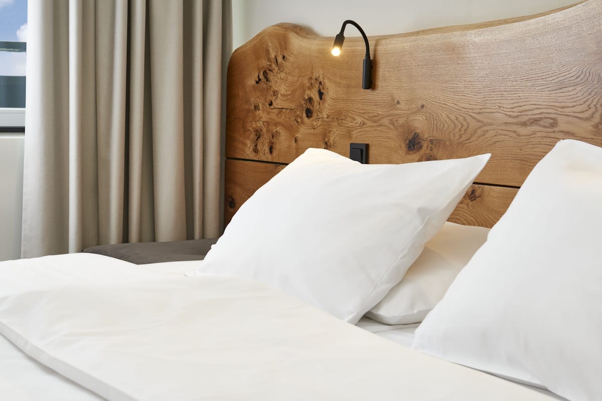 A neatly made bed with white linens in a modern hotel room.