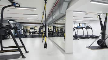 A gym with treadmills, weight machines, and suspension straps.