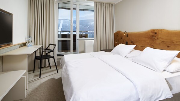 A hotel room with a bed, a desk, a chair, and a television.