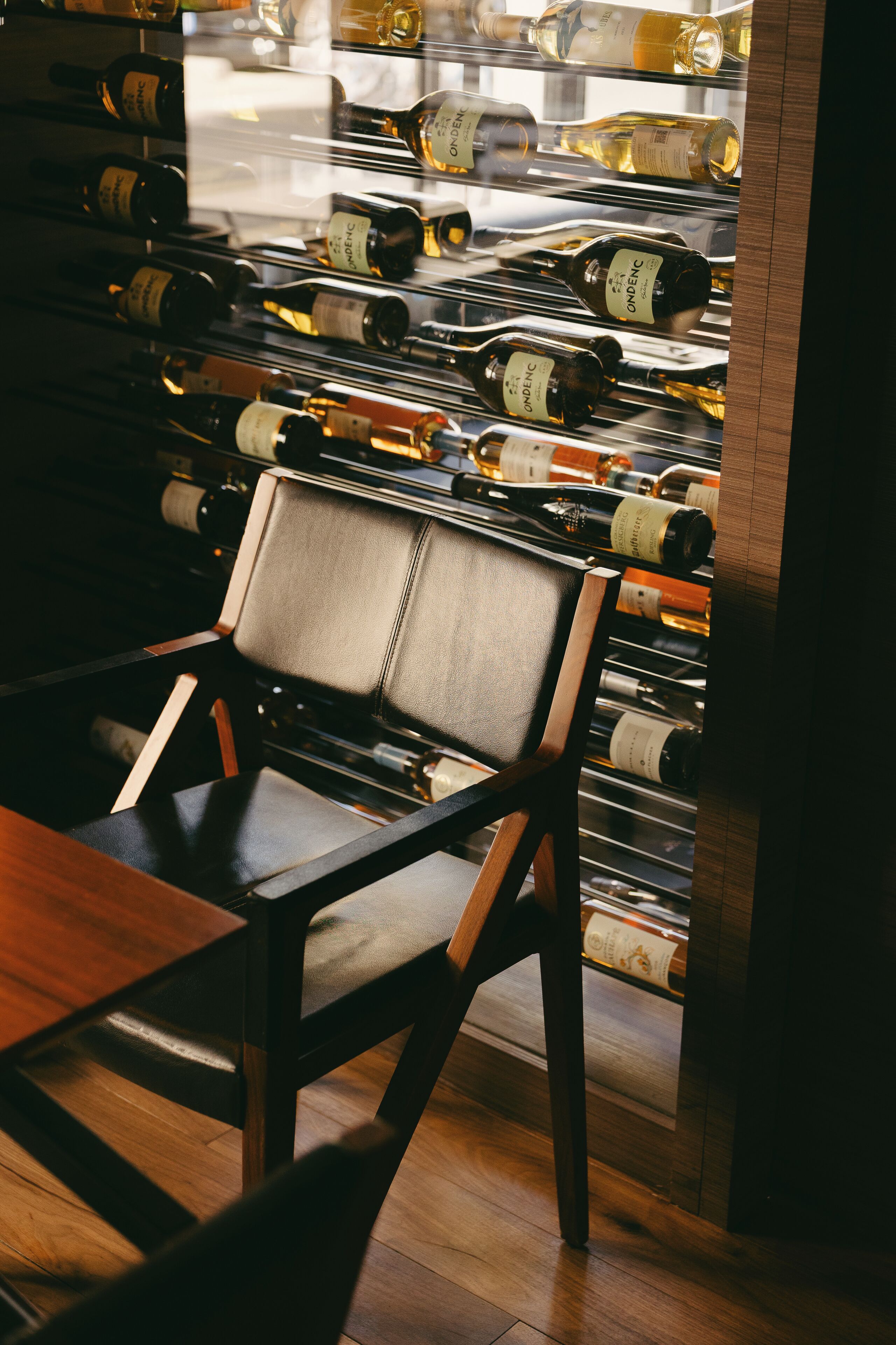 A chair in front of a wine rack with bottles.