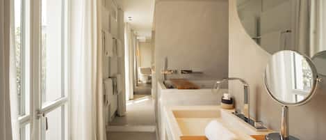Un baño moderno con un espejo grande, un tocador de madera y una bañera.