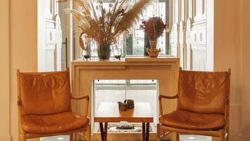 Un coin repas comprenant deux fauteuils en cuir, une table en bois et un vase avec des plantes séchées, posé sur une console.
