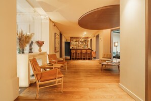 A spacious room with wooden flooring, a bar area, and seating arrangements. - Hôtel de Nell (Paris)