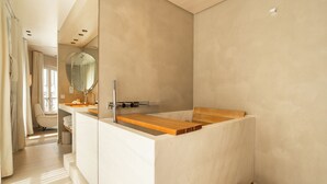 A modern bathroom with a wooden vanity, a large mirror, and a bathtub. - Hôtel de Nell (Paris)