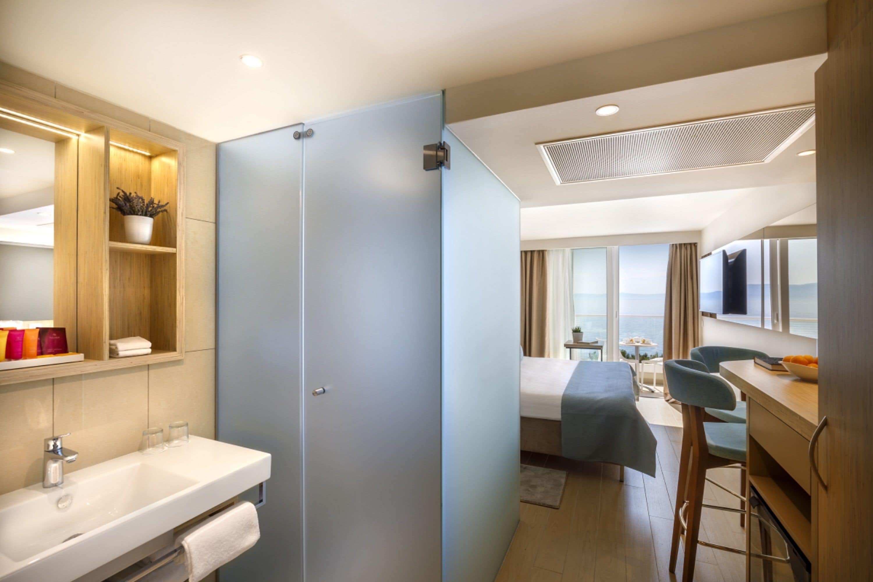Una camera d'hotel moderna con bagno, zona salotto con vista e area pranzo.