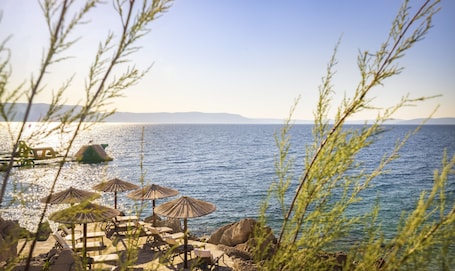 En la playa, sillas reclinables de playa, sombrillas, toallas de playa. Girandella Resort, Valamar Collection