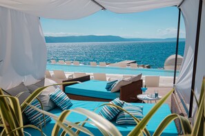 A balcony with a view of the sea, a pool, and a bed with blue bedding. - Girandella Resort, Valamar Collection (Labin)