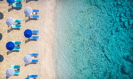En la playa, sillas reclinables de playa, sombrillas, toallas de playa. Girandella Resort, Valamar Collection