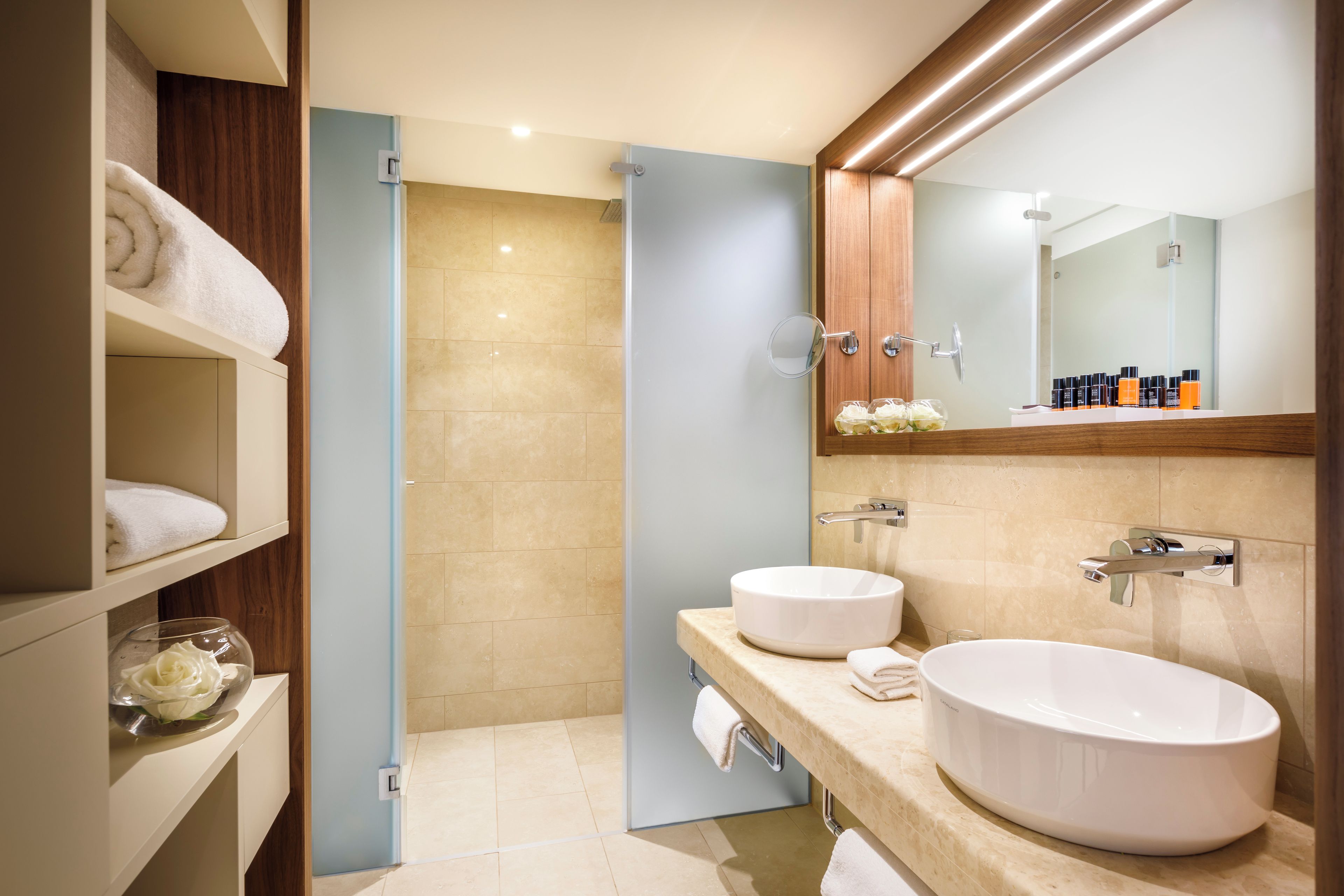 A modern bathroom with two sinks, a shower, and a vanity with a mirror.