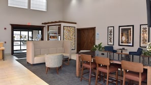 A lobby with a reception desk, a seating area with a sofa and chairs, a dining table with chairs, and a large window with a view. - Holiday Inn Express Mount Pleasant-Scottdale by IHG (Mount Pleasant)