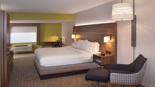Habitació d'hotel amb llit, taules de nit, escriptori, cadira i làmpada penjada a la paret.