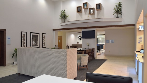 A hotel lobby with a reception desk, seating area, and framed artwork on the walls.