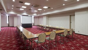 A conference room with a long table, chairs, a projector screen, and a red carpeted floor. - Comfort Hotel Sakai (Sakai)