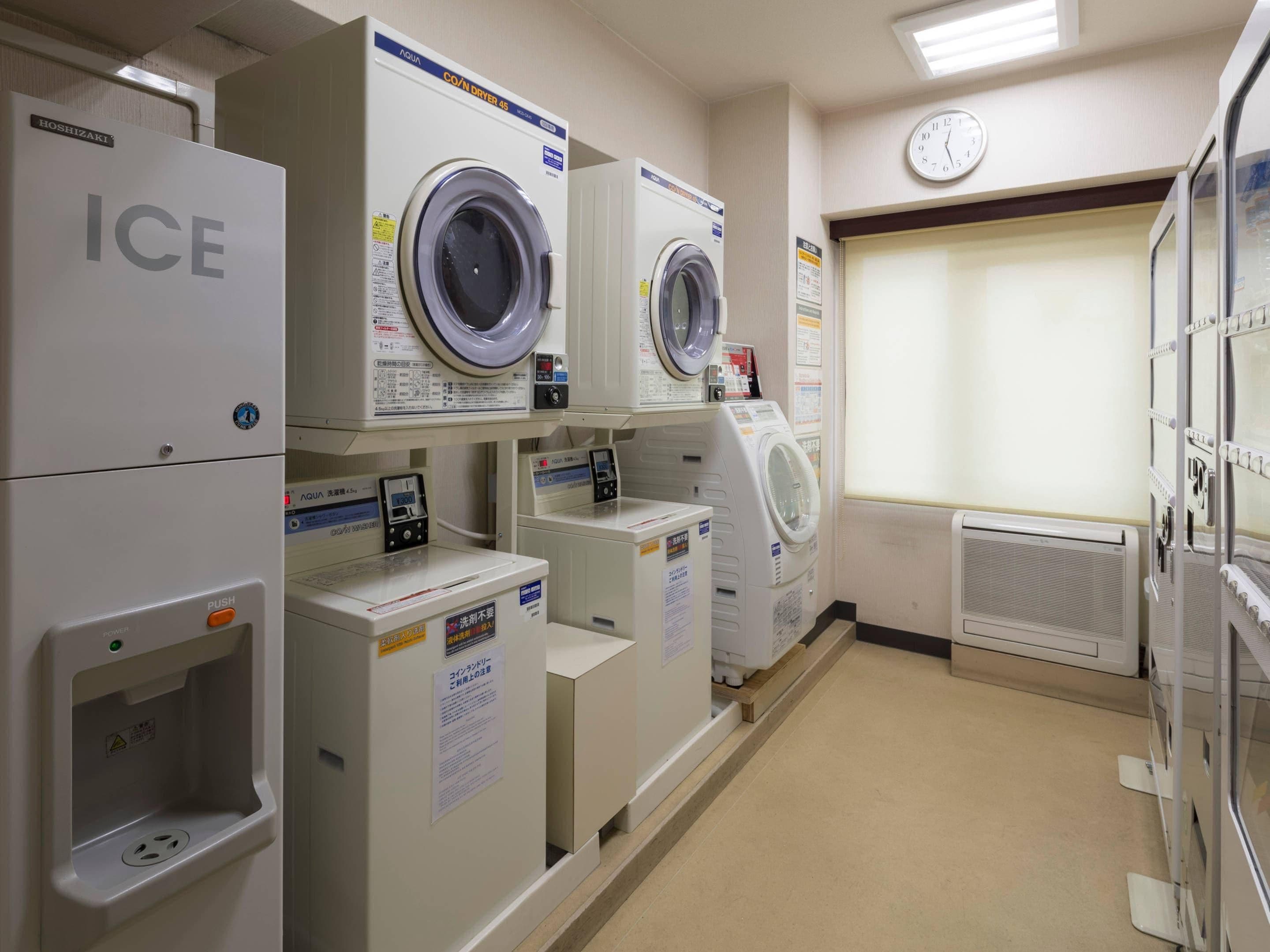 Une laverie équipée de plusieurs machines à laver, d’une horloge et d’un système de ventilation.