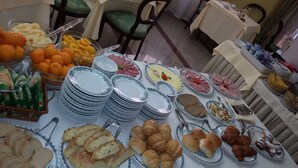 A buffet table with various food items and stacked plates. - Hotel Ipanema (Taormina)