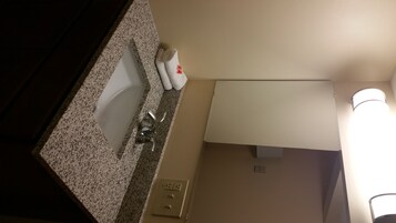 Un baño con lavamanos, espejo y perchero para toallas.
