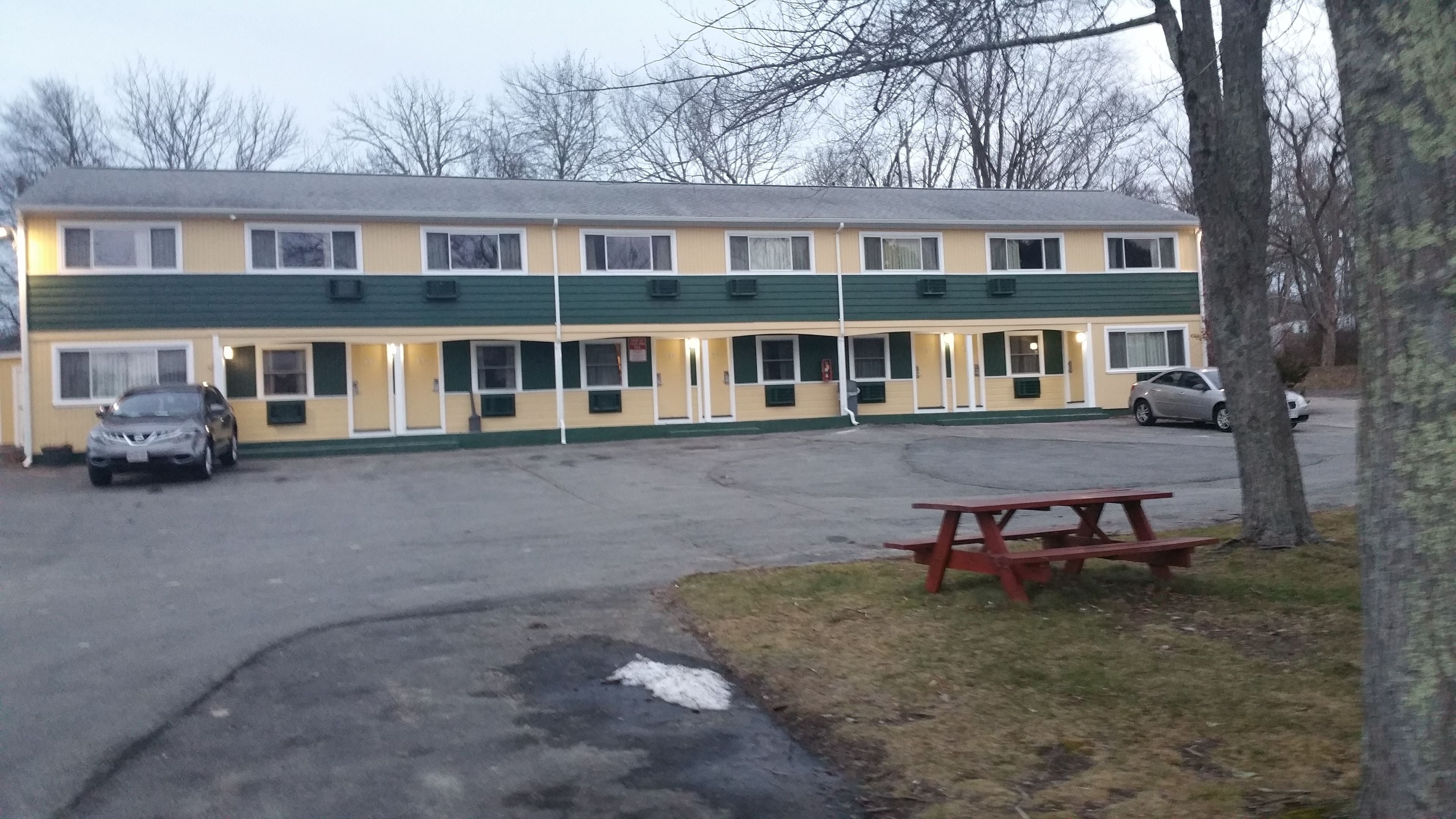 A motel with a parking lot, a picnic table, and a car parked in front.