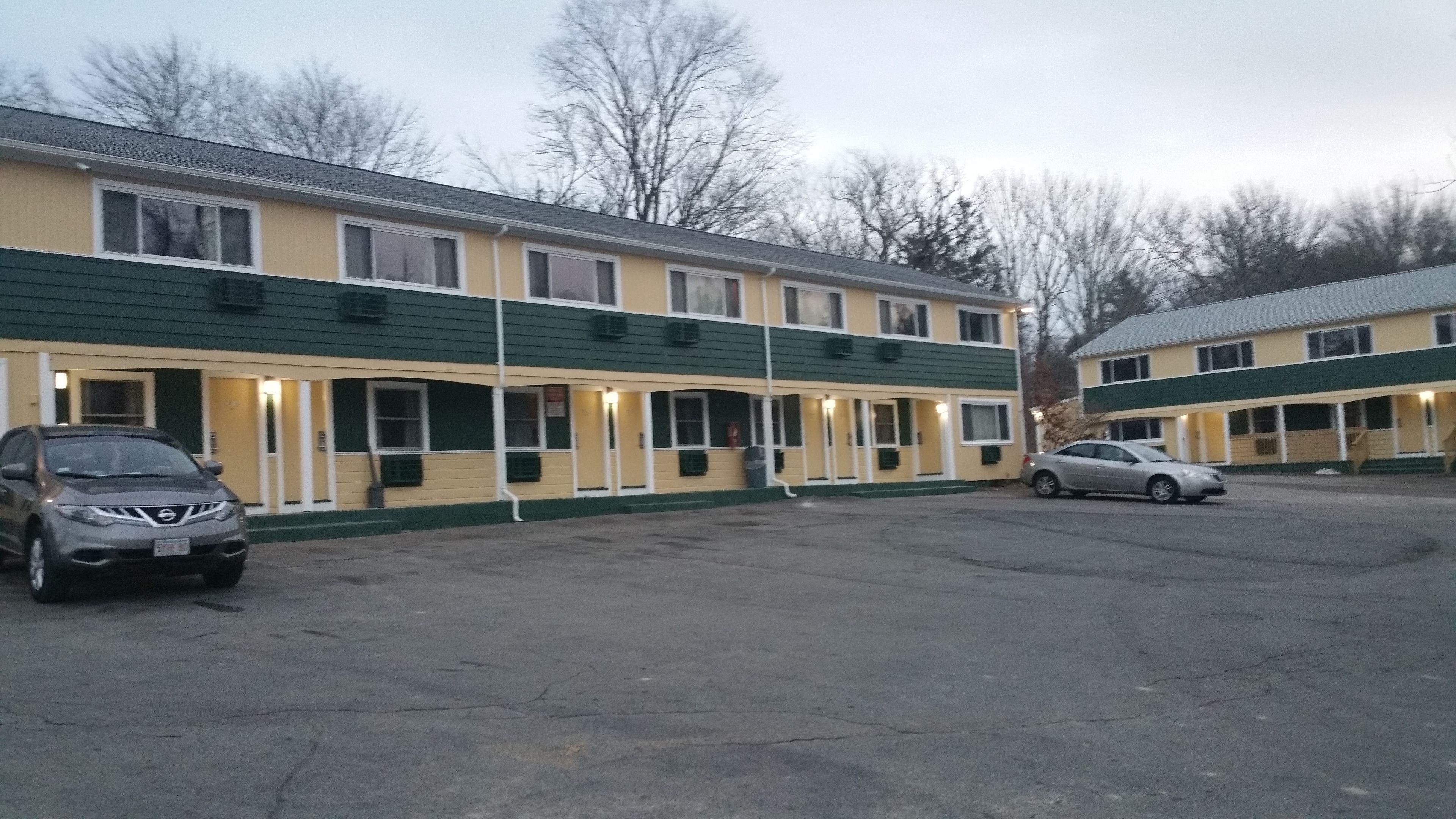 A motel with two-story buildings, a parking lot, and a few parked cars.