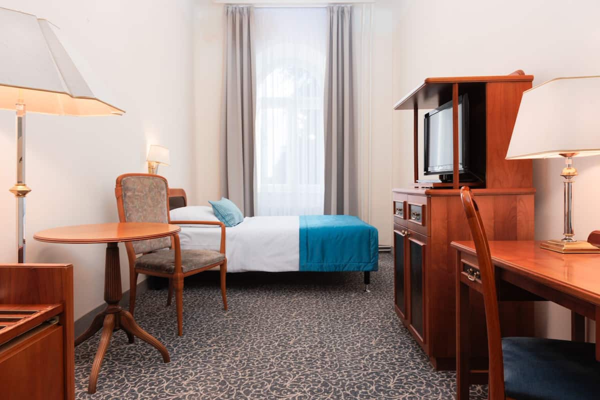 Ein Hotelzimmer mit einem Bett, einem Schreibtisch, einem Sessel, einem Fernseher und einer Lampe.