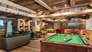 Un interior de madera con mesa de billar, sofás y una pared de piedra.