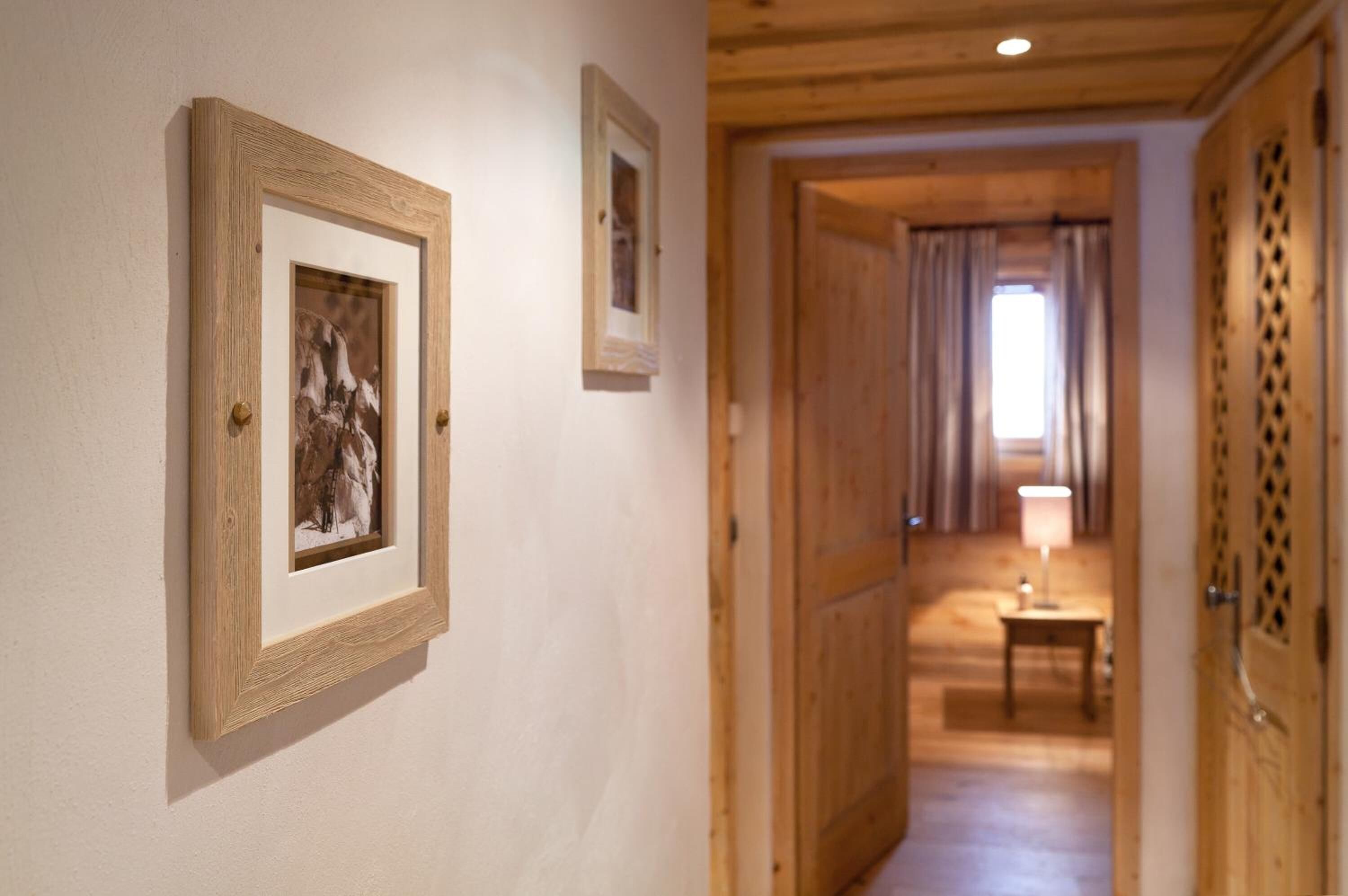 Un pasillo con puertas de madera y cuadros en la pared.