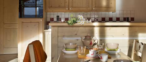 A kitchen with wooden cabinets, a dining table set with dishes, and a towel on a chair.