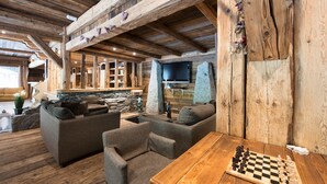 Un interior de madera acogedor con sofás, una mesa de madera y un tablero de ajedrez.