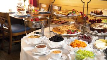 A buffet table with various food items and a three-tiered serving stand.